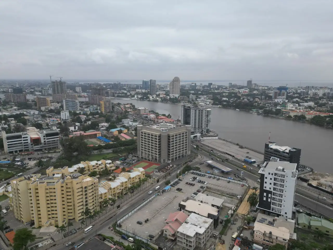 Aerial shot capturing Lagos cityscape with modern buildings by Lagos Lagoon under an overcast sky.